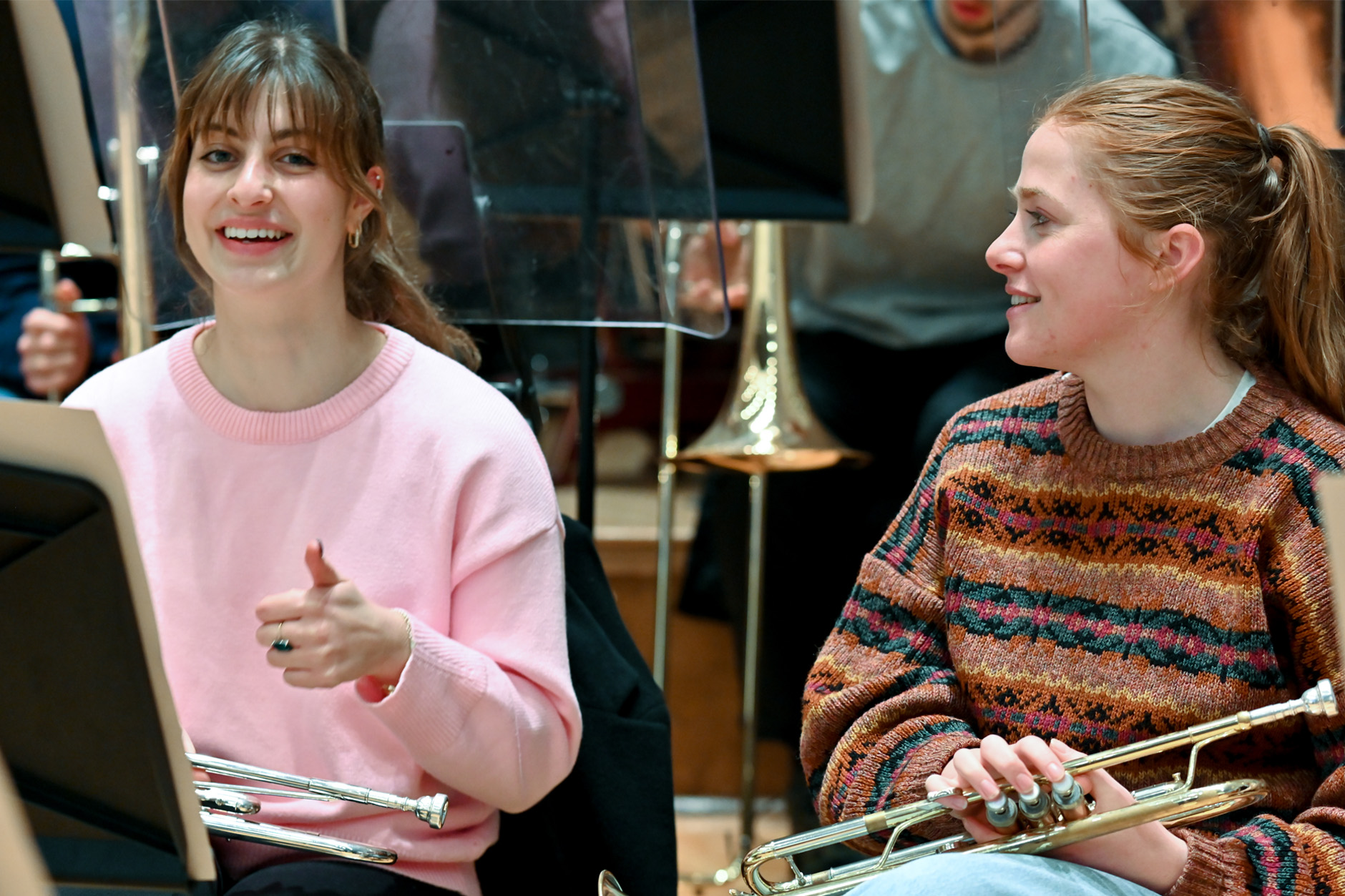 Two female trumpet students chatting and resting in an orchestral rehearsal